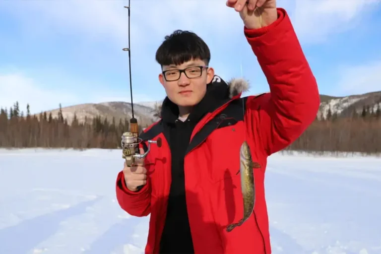 a man in a red jack ice fishing at chena
