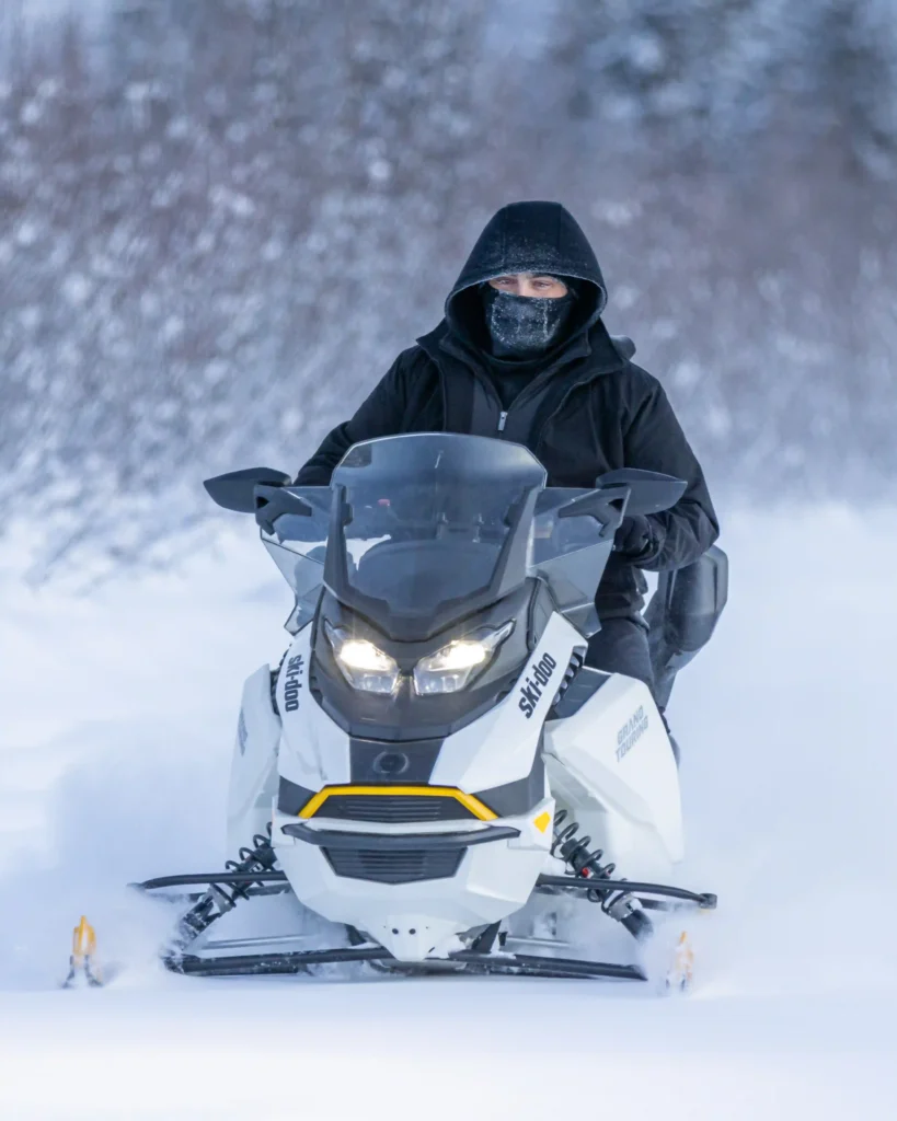 Front view of a rider in full winter gear on a snowmobile trail in interior Alaska